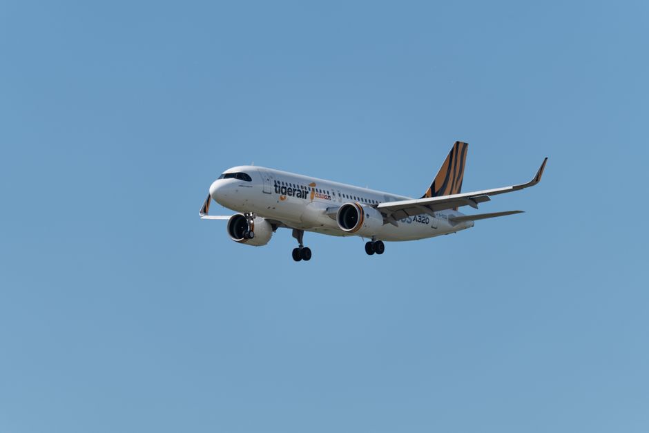 A Tigerair Airbus A320 flying through a clear blue sky, showcasing air travel.