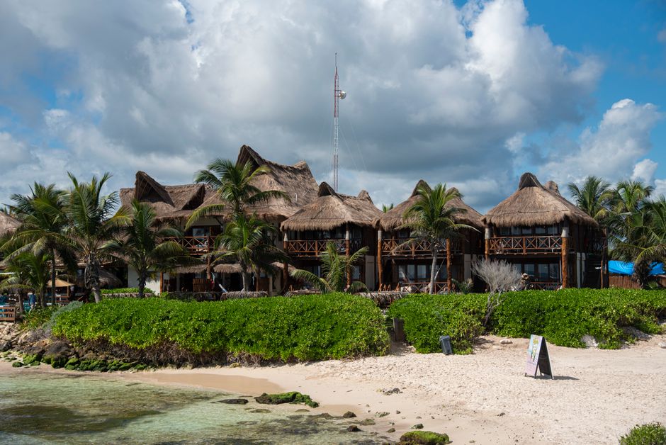 Tropical beach resort with palapa roofs and palm trees in Tulum, Mexico.