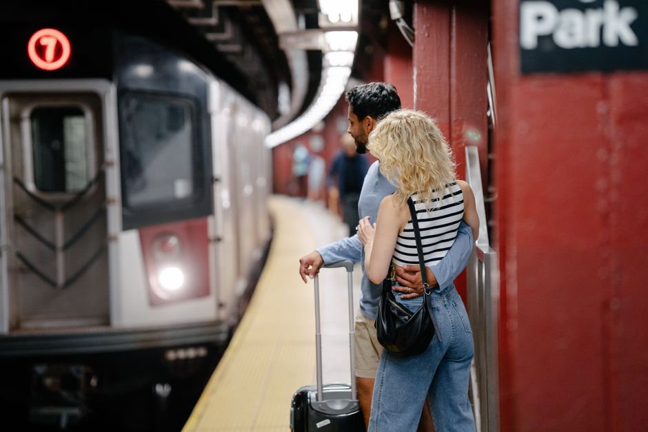 A couple embraces while waiting for a subway train at an urban station platform.