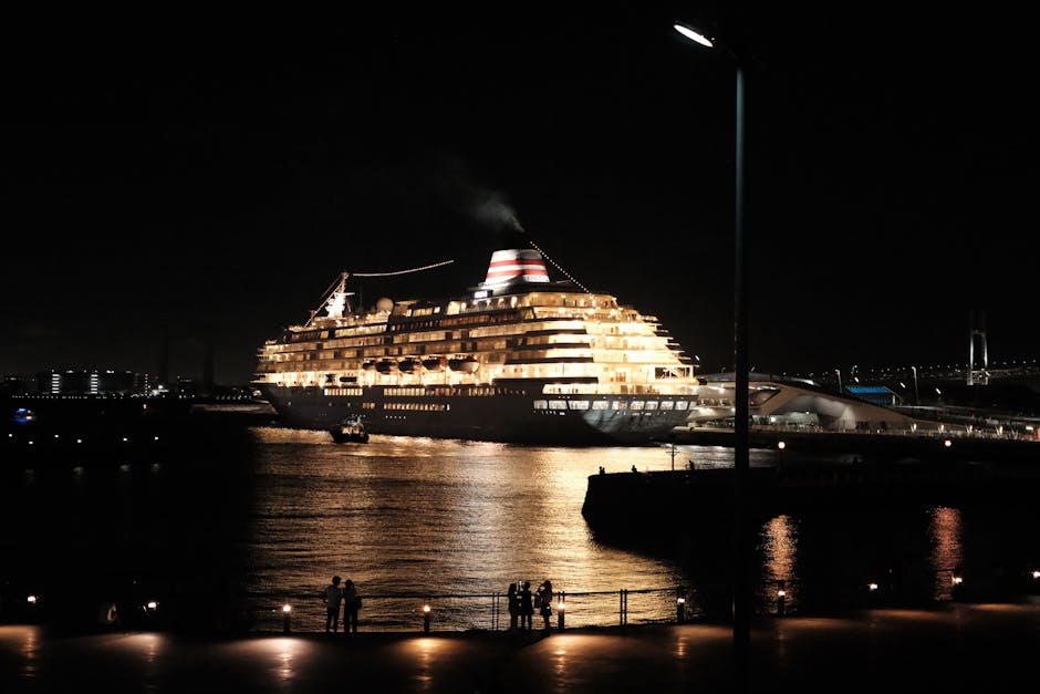 Illuminated cruise ship in night port with city lights, peaceful scene.