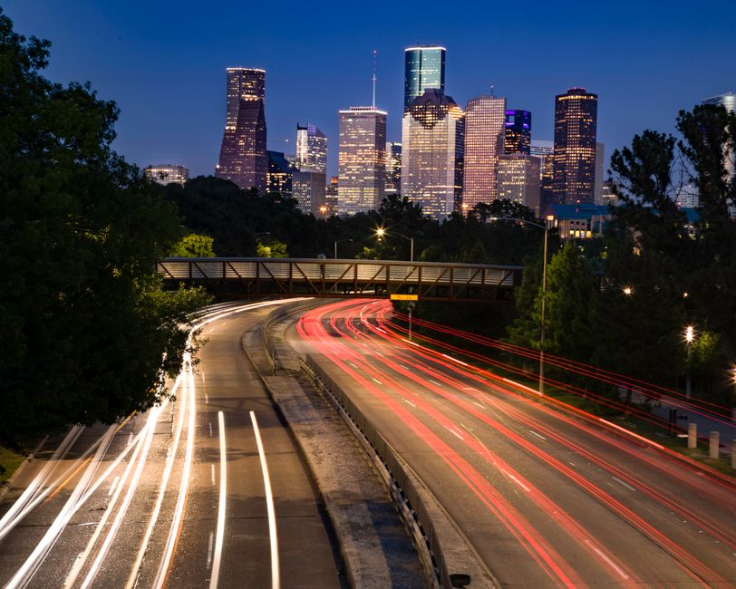 Long exposure shot of Houston's skyline at night with vibrant light trails leading into th