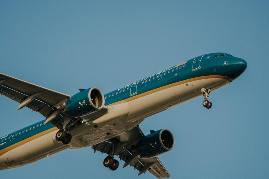A Vietnam Airlines airplane flying against a clear blue sky, captured from a low angle.