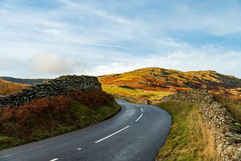 Beautiful winding road with stone walls through vibrant countryside and hills. Perfect for travel and nature enthusiasts.