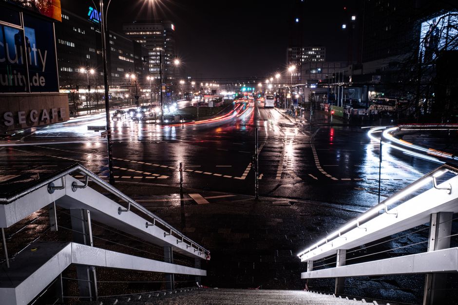 Vibrant Berlin cityscape at night with dynamic light trails and wet streets reflecting lights.