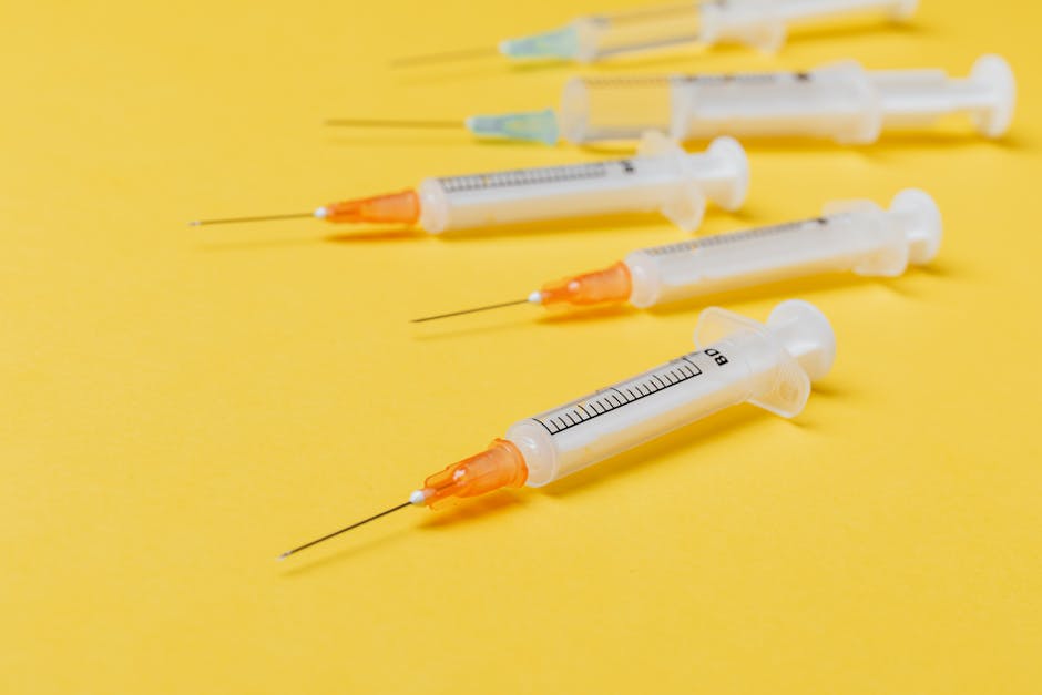 Medical plastic disposable syringes of different sizes with orange and green needle hubs placed on yellow background without protective cover