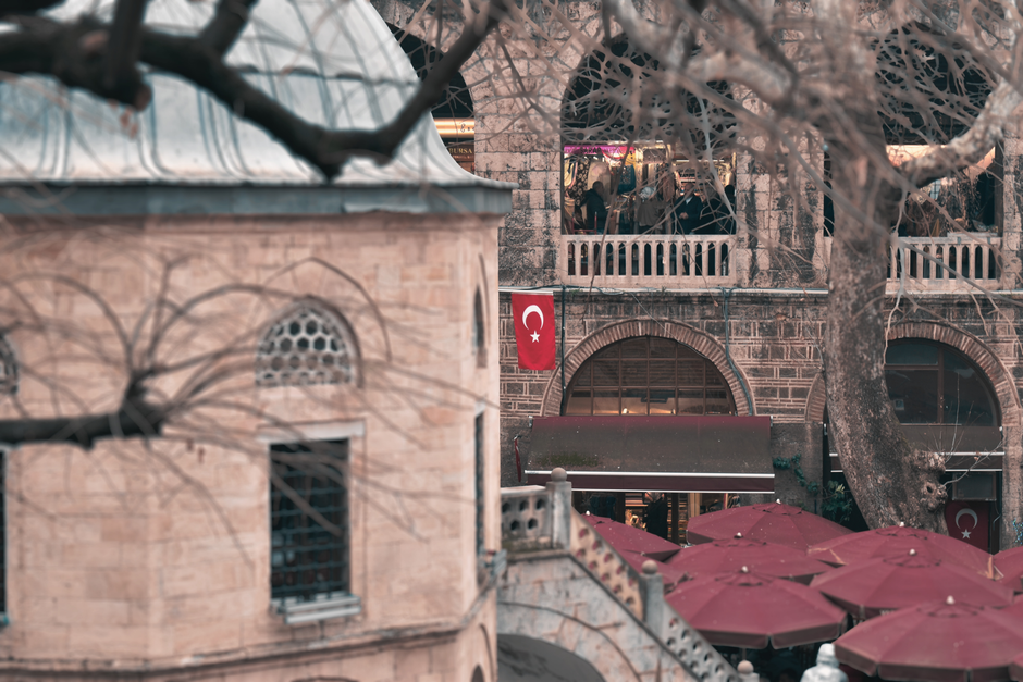 A scenic view of Bursa's historic architecture with Turkish flag and café.