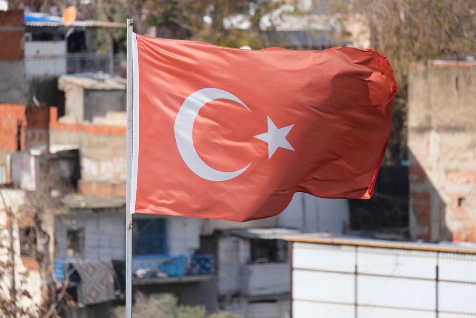Turkish flag waving in front of an urban background, symbolizing national pride.