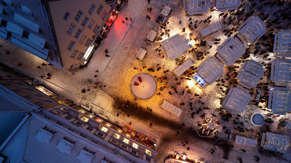 Aerial perspective of Tallinn's festive Christmas market at night with glowing lights and snow.